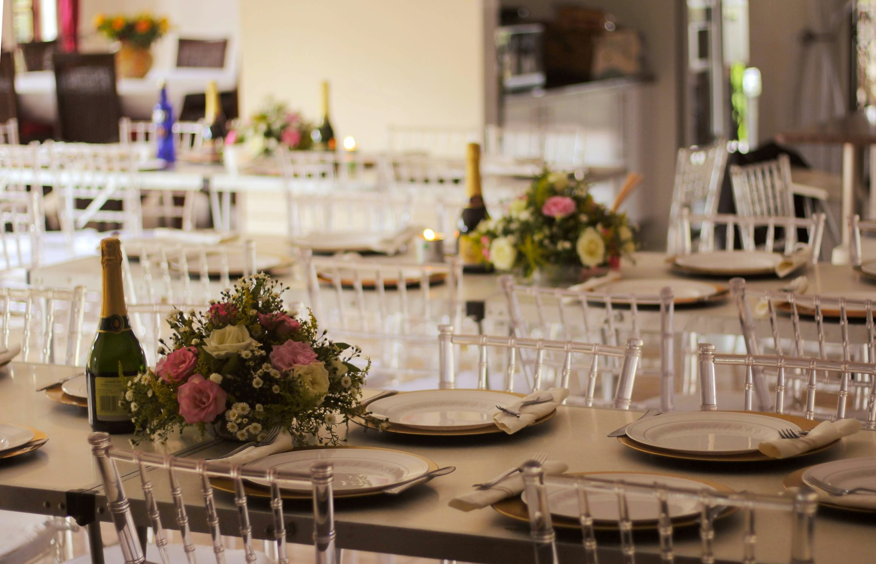 Tables laid with gold chargers and flowers for a private party